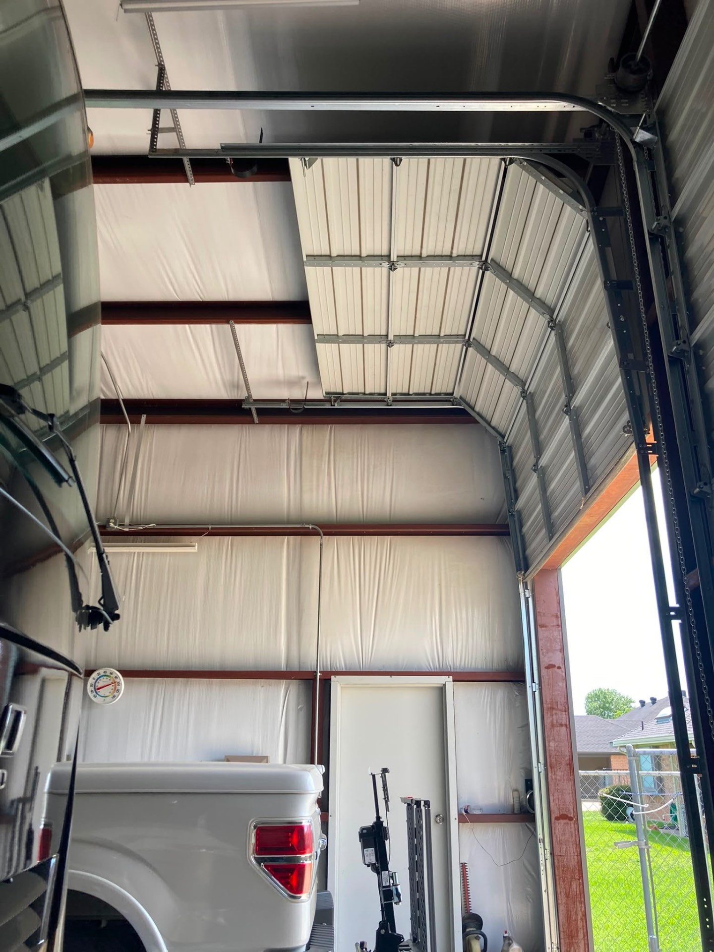 Commercial overhead door with new track and chain hoist inside an insulated shop