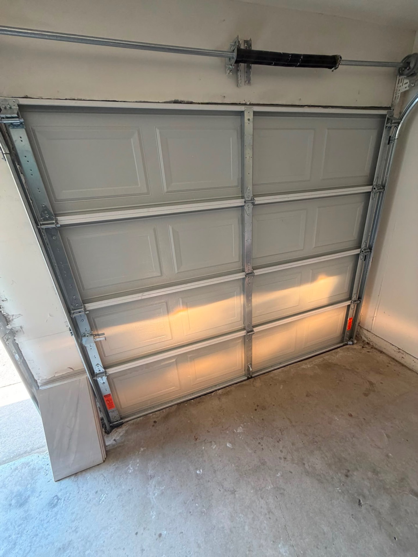 Raised-panel garage door with new torsion spring, hinges, and rollers installed